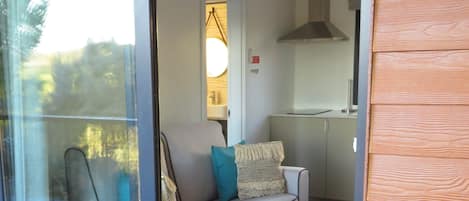 Un intérieur moderne avec une porte vitrée donnant sur un balcon, un canapé avec des coussins et une petite table ronde.