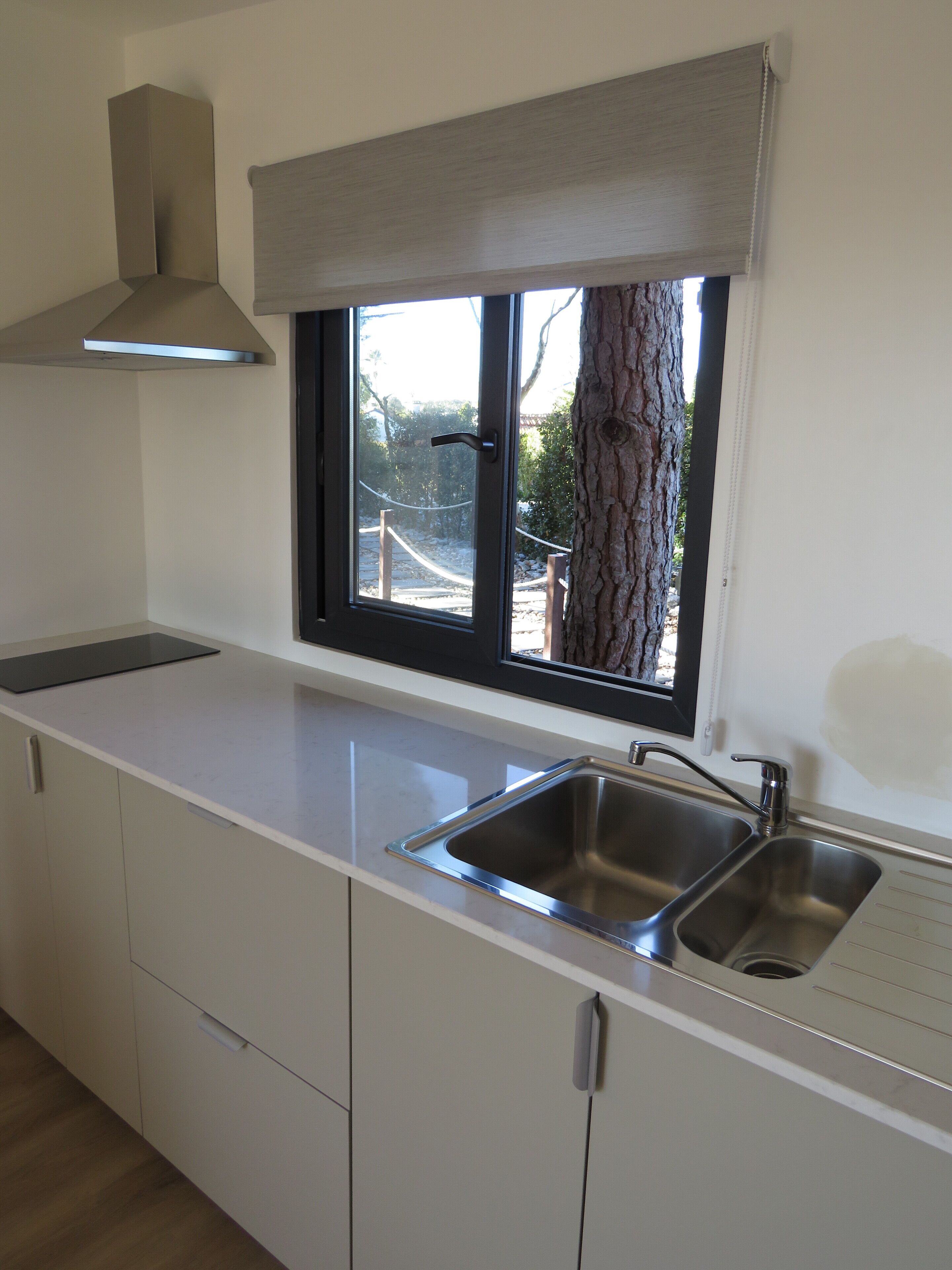 Una cocina con ventana, un lavamanos y armarios.