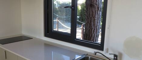 Una cocina con ventana, un lavamanos y armarios.