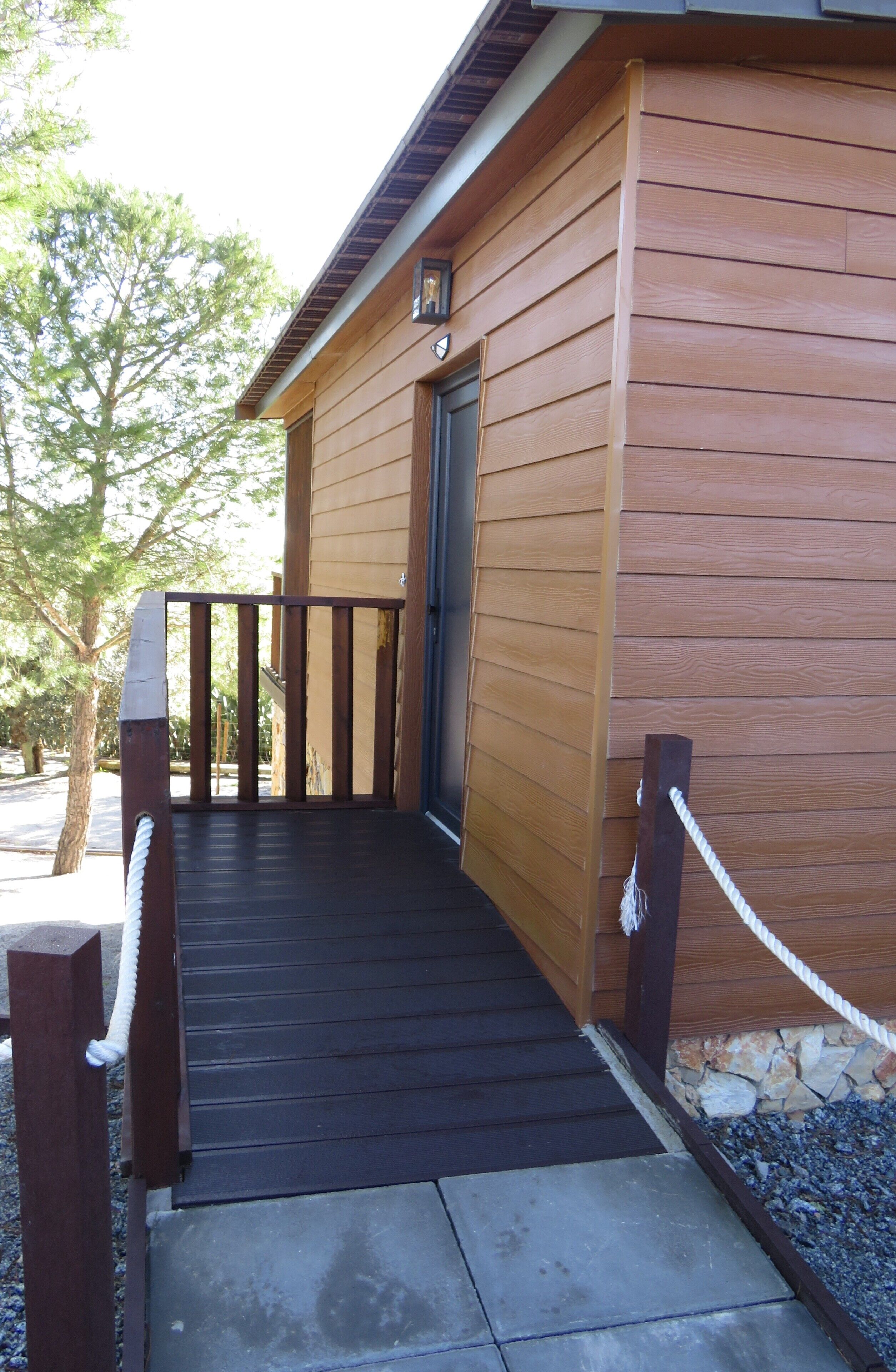 A wooden building with a dark wooden deck leading to a door.