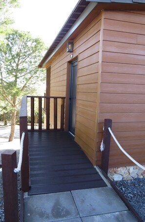 A wooden building with a dark wooden deck leading to a door. - 1-Bedroom Bungalow (Ciborro)