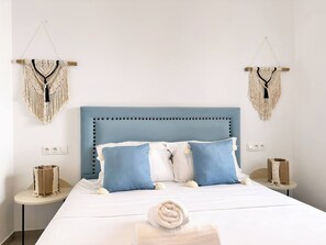 A bed with a blue headboard, two macramé wall hangings, and a white towel on the bed. - Appartement Rayhana Sidi Bou Said (Sidi Bou Said)