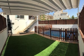 A covered outdoor area with a pool, a wooden fence, and a staircase leading to a building. - Family Vacation Home (La Ràpita)