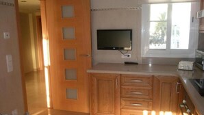Uma cozinha com armários de madeira, televisão integrada e janela que proporciona luz natural.