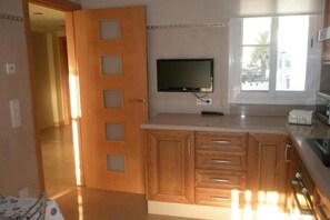Eine Küche mit Holzausstattung, einem integrierten Fernseher und einem Fenster, das für natürliches Licht sorgt.