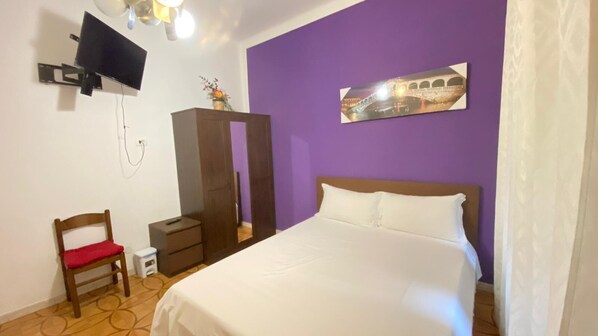 A bedroom with a bed, a TV mounted on the wall, a wardrobe, and a small table with a chair. - Three-Bedroom Family Apartment 25 (Venezia)