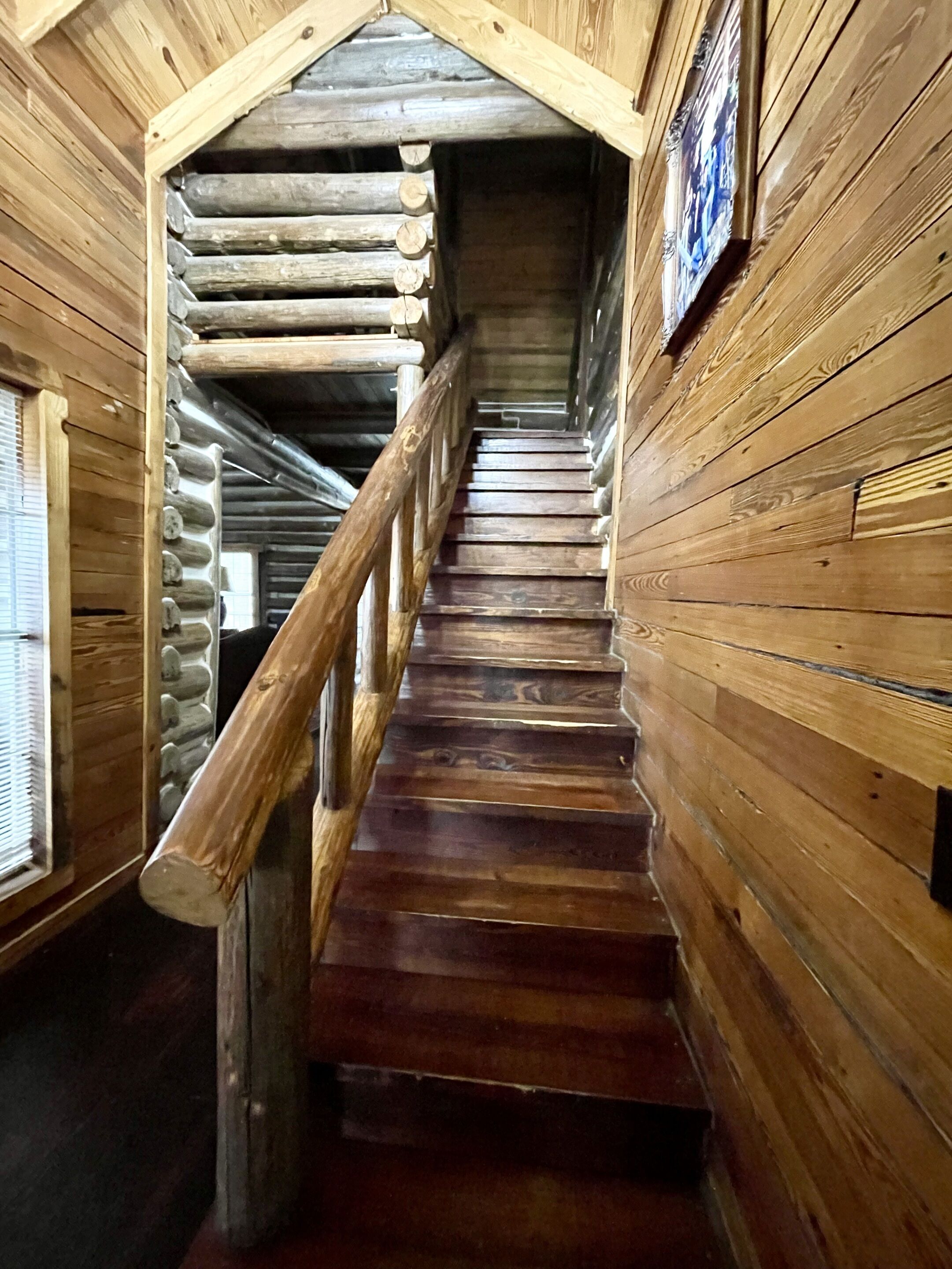 A wooden staircase with a wooden railing leading to a higher level.