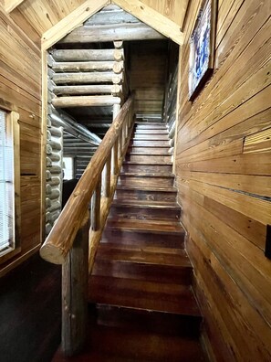 A wooden staircase with a wooden railing leading to a higher level. - Presley Deluxe Log Cabin (Hartsfield)