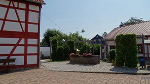 A courtyard with cobblestone paving, a traditional half-timbered building, and a flower bed with pink flowers. - Family-Friendly Vacation Rental (65 m²) Near the Vessertal Nature Reserve (Schleusingen)