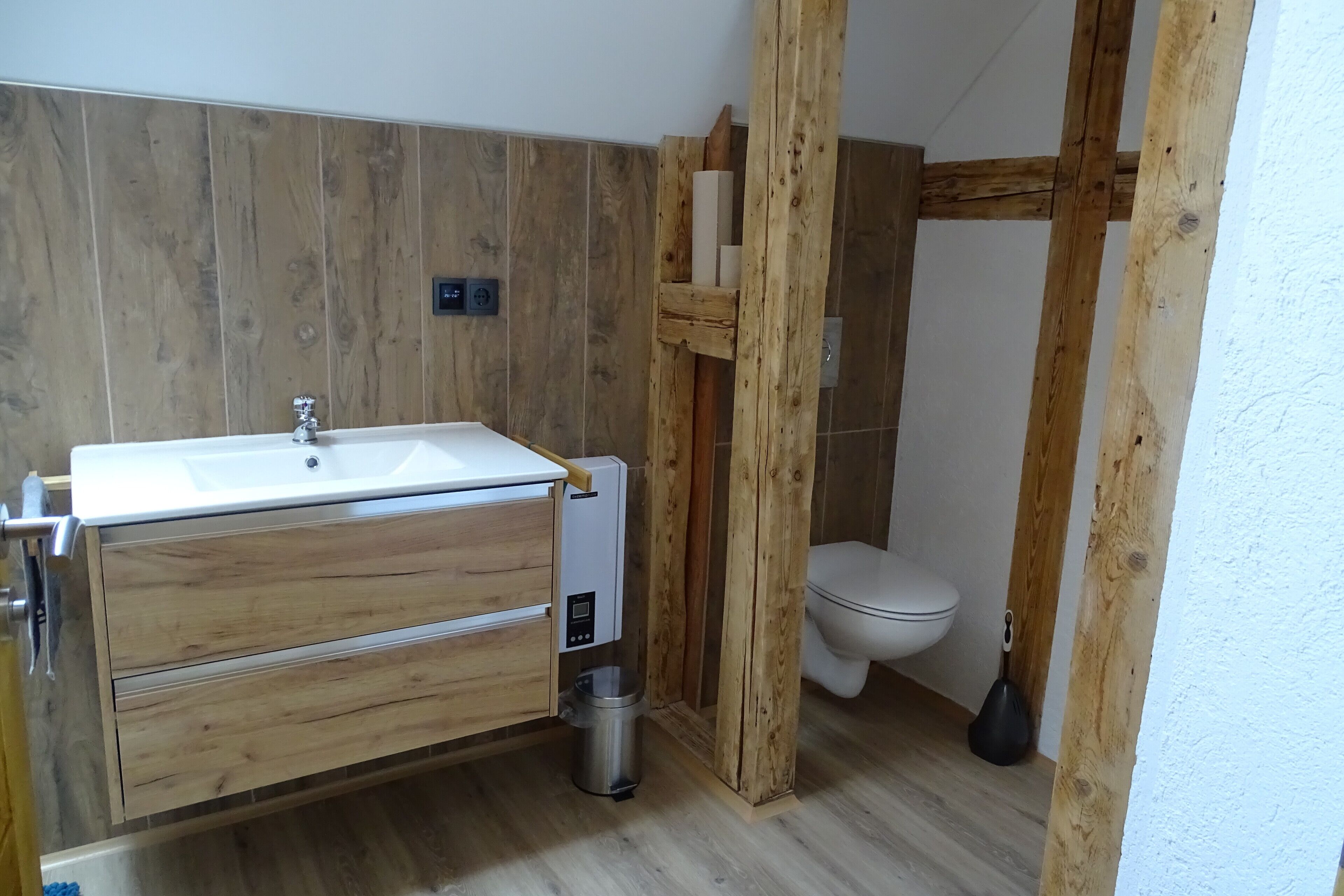 Ein Badezimmer mit Holzwaschtisch, Toilette und Duschbereich.