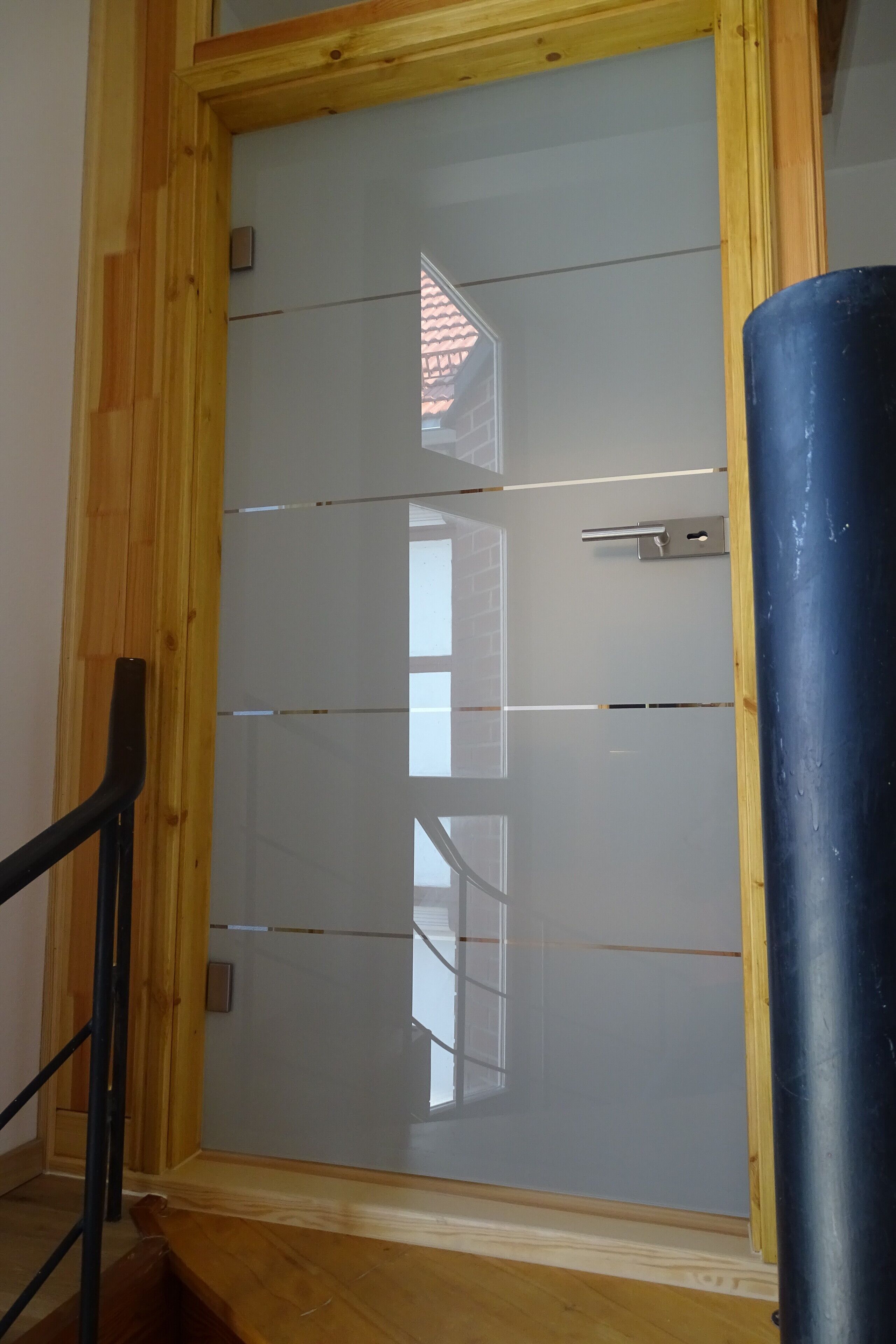 Ein Zimmer mit einer holzrahmenverzierten Tür, einer schwarzen Metallhandläufe und einem großen, blauen zylindrischen Gegenstand.