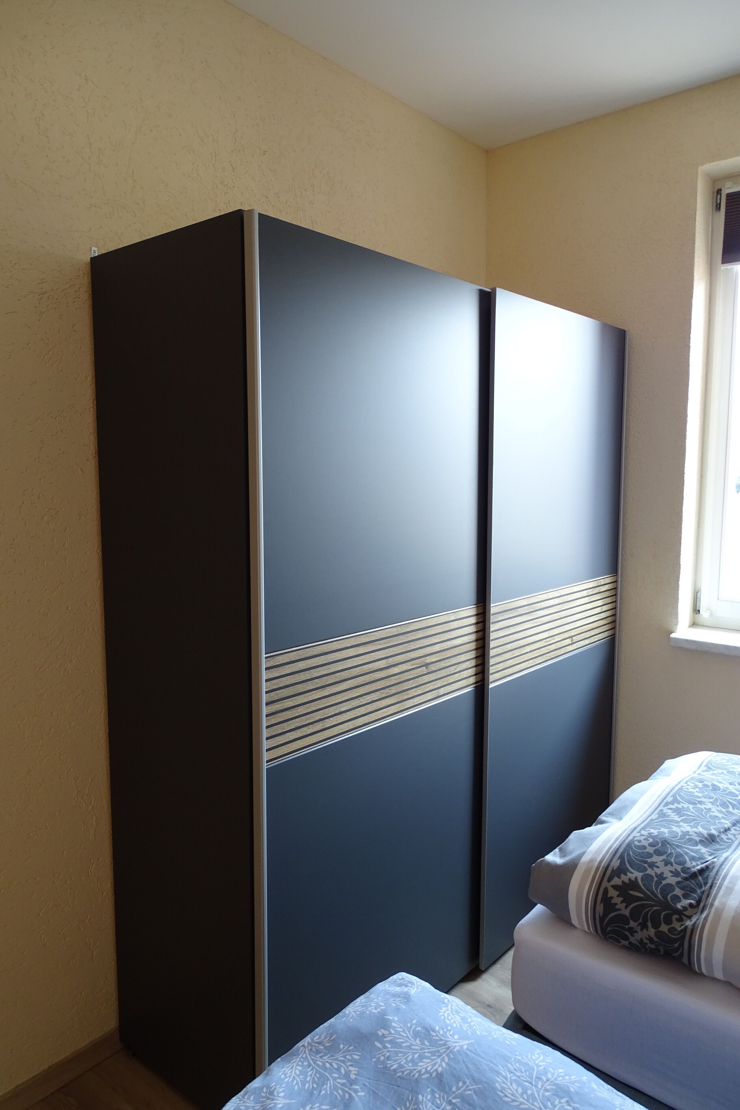 Une chambre à coucher avec un lit, une armoire et une fenêtre.