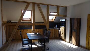 A kitchen with wooden beams, a dining table with chairs, and a built-in oven.