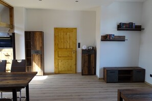A room with a wooden door, a bookshelf, a small cabinet, and a dining table.