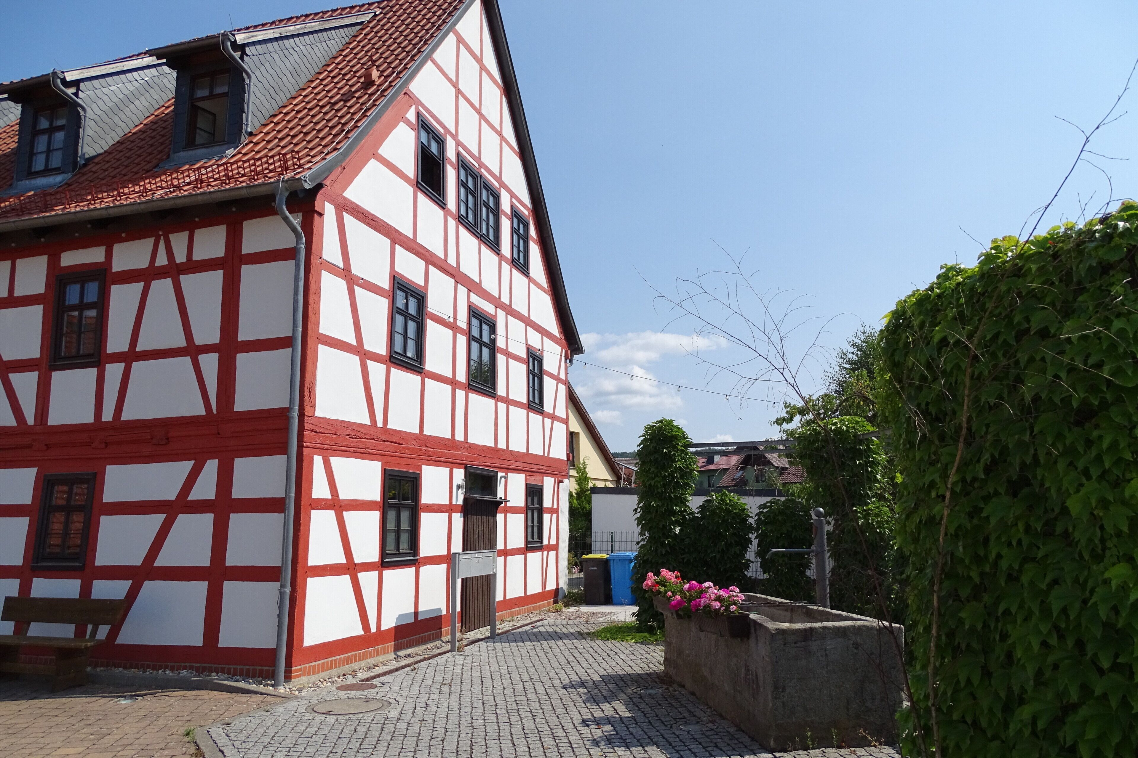 Ein traditionelles Fachwerkhäuschen mit geneigtem Dach und einem gepflasterten Innenhof.