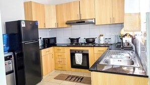 Een moderne keuken met houten kastjes, een zwarte koelkast, een magnetron, een fornuis en een spoelbak.