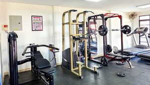 Een sportschool met diverse fitnessapparaten, waaronder een bankdrukrek, een squatsysteem en een loopband.