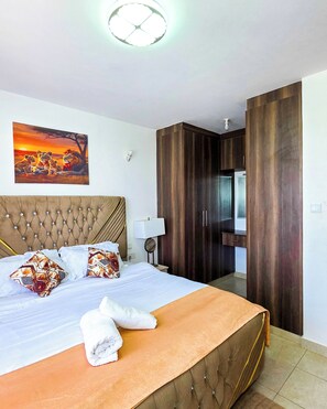 Ein Hotelzimmer mit einem großen Bett, einem Kopfteil, einem Gemälde, einem Kleiderschrank und einem Badezimmerspiegel.