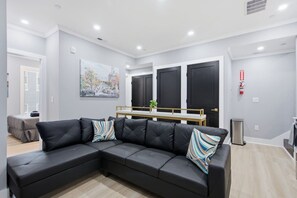 Uma sala de estar moderna com um sofá seccional, um banco de madeira e um quadro na parede.