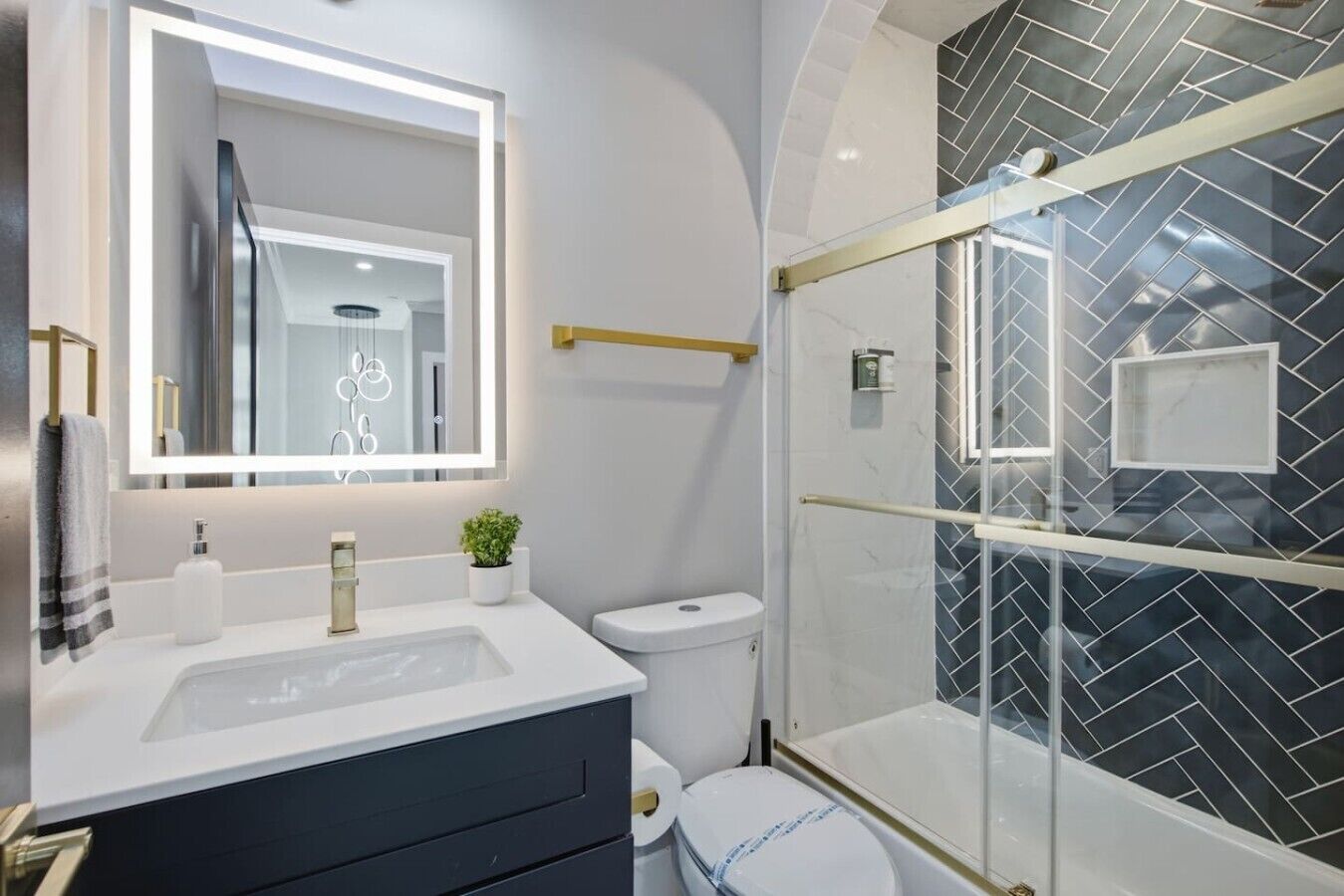 Une salle de bain moderne avec une douche à parois de verre, un grand miroir et un meuble-lavabo blanc.
