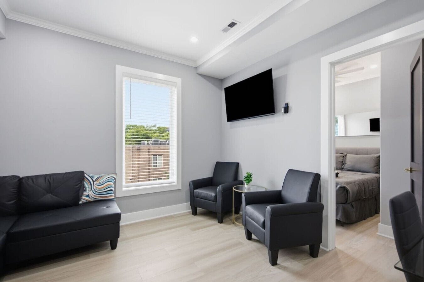 Een moderne woonkamer met een bank, fauteuils, een flatscreen-televisie en een plantentafel.