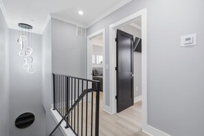Ein modernes Interieur mit Treppe, einer schwarzen Tür und einer Deckenleuchte.