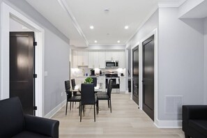 Una cocina moderna con armarios blancos, una isla central y un comedor con sillas negras.