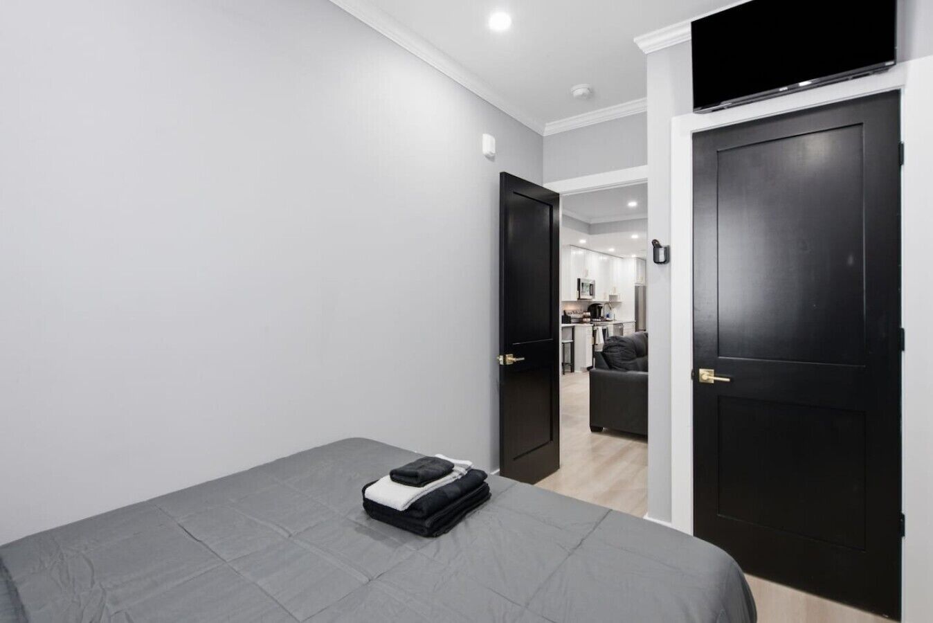Een slaapkamer met een bed, een koffer en een deur naar een kitchenette.