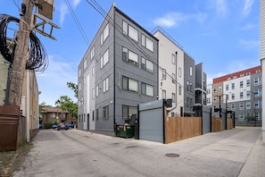 A modern multi-story building with a grey facade, large windows, and a gated entrance. - H Street Hideaway | Stylish 4BR in NE DC (Washington)