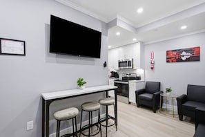 Een compacte woonruimte met kitchenette, flatscreen televisie, een klein barretje en zitplaatsen.