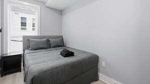 Une chambre à coucher avec un lit, une table de chevet et une fenêtre avec des stores.
