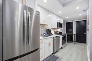Une cuisine moderne dotée d’appareils électroménagers en acier inoxydable, de meubles blancs et d’une porte noire.