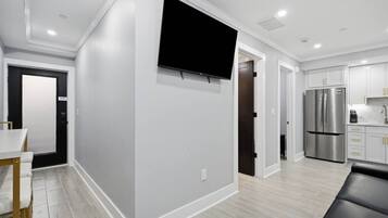 Una cocina moderna con refrigerador integrado, un televisor de pantalla plana montado en la pared y un comedor con mesa y sillas.
