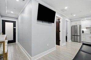 Una cucina moderna con frigorifero integrato, una TV a schermo piatto montata a parete e un'area pranzo con tavolo e sedie.