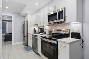 A modern kitchen with stainless steel appliances, white cabinetry, and a marble countertop. - Luxury 4BR Condo | Minutes to Capitol & H Street (Washington)