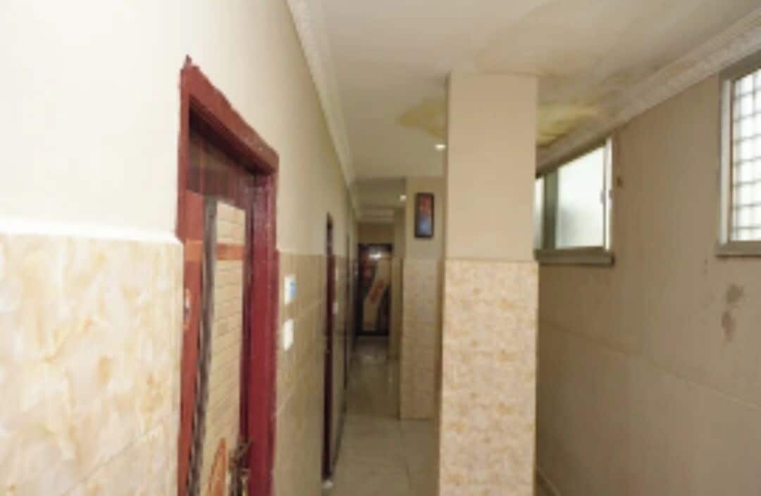 A corridor with a door on the left, a window on the right, and a hallway extending into the distance.