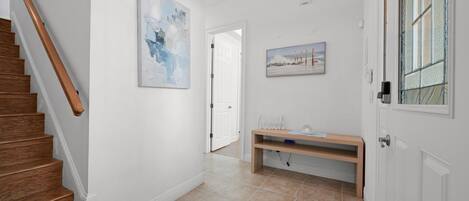 A hallway with a wooden staircase, a bench, and a door.