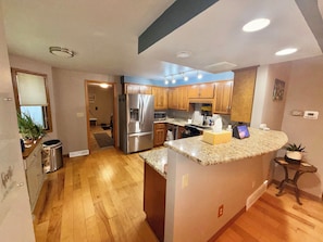 A modern kitchen with wooden cabinets, stainless steel appliances, and a granite countertop.