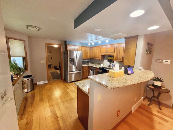 A modern kitchen with wooden cabinets, stainless steel appliances, and a granite countertop. - Spacious 5 bedroom kid friendly home. Private backyard. 1.5 miles from Lambeau (Green Bay)