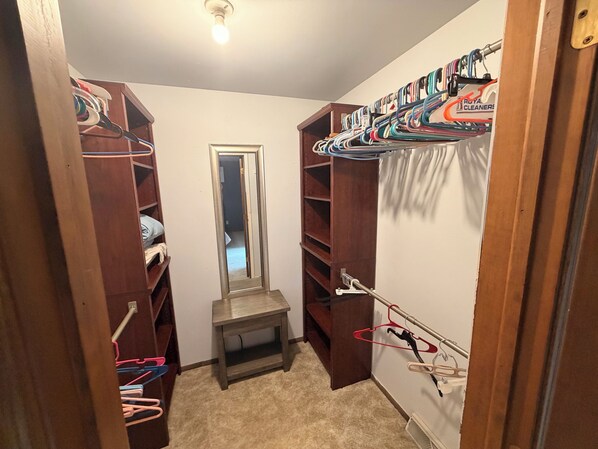 A walk-in closet with wooden shelving, a mirror, and a small table.