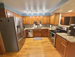 A kitchen with wooden cabinets, stainless steel appliances, and a granite countertop. - Spacious 5 bedroom kid friendly home. Private backyard. 1.5 miles from Lambeau (Green Bay)