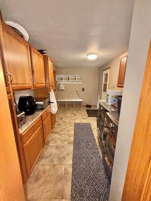 A compact kitchen with wooden cabinets, a toaster, a coffee maker, and a washing machine.