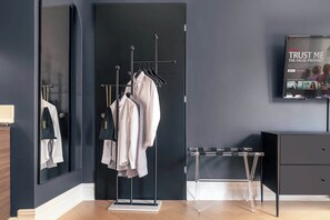Ein modernes Zimmer mit einem Spiegelkleiderschrank, einem Fernseher, der einen Film zeigt, und einer schlichten Möblierung.