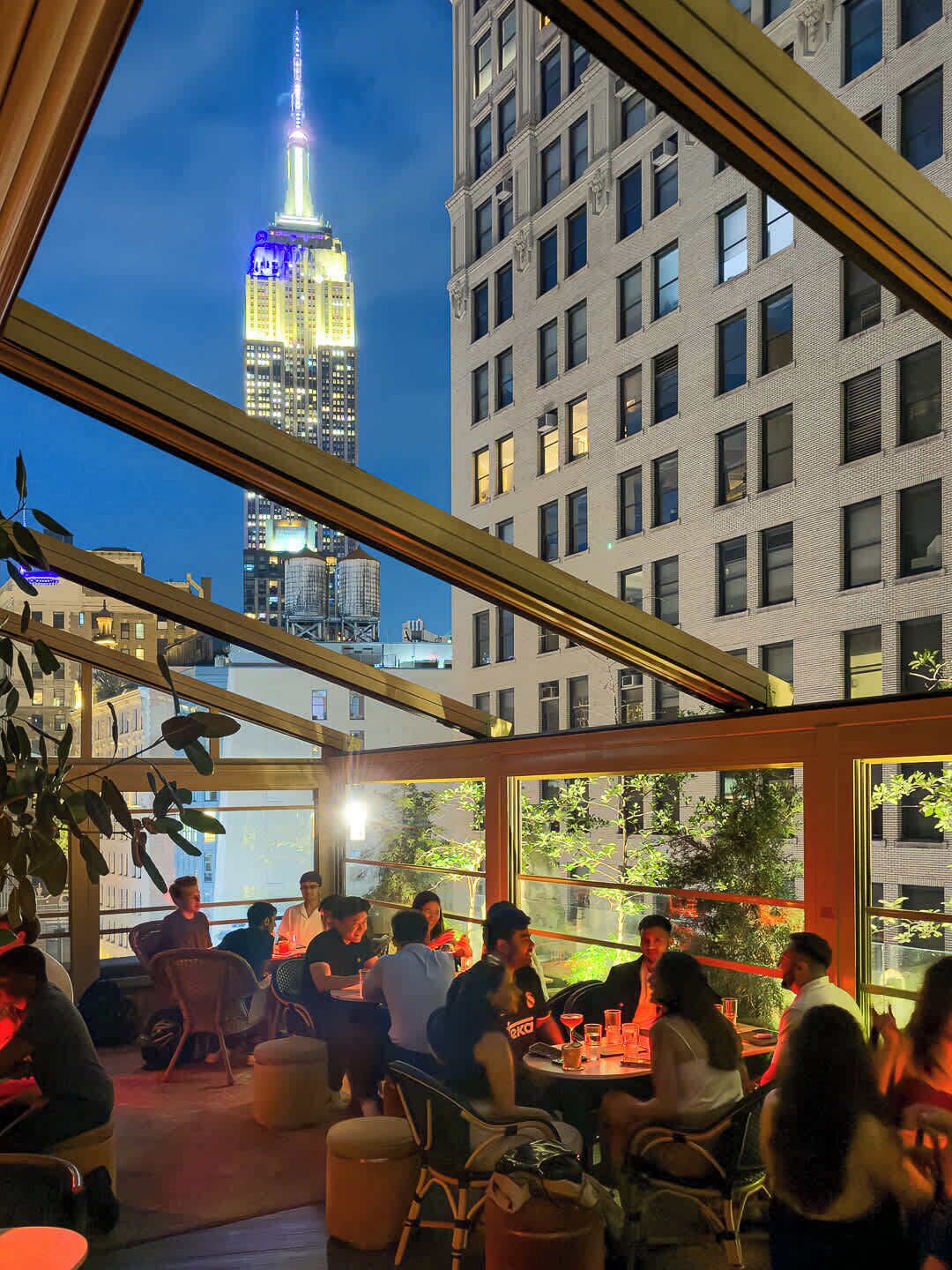 An outdoor seating area with tables and chairs, overlooking a cityscape with a prominent building.