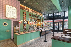 Ein Blick in eine Gelateria, mit einer Speisekarte, einer Theke mit Gelato-Pobergstücken und einem Ausblick auf die Straße.