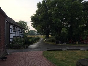A rural pathway leading to a traditional half-timbered house with a brick wall and a paved walkway. - NEW! Granny Flat in Bönen (Bönen)