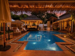 A swimming pool with a tiled edge, surrounded by outdoor seating and a covered area with string lights. - private villa 4bedroom 5 bathrooms ,private pool,  beach just a 1-minute to walk (Surat Thani)