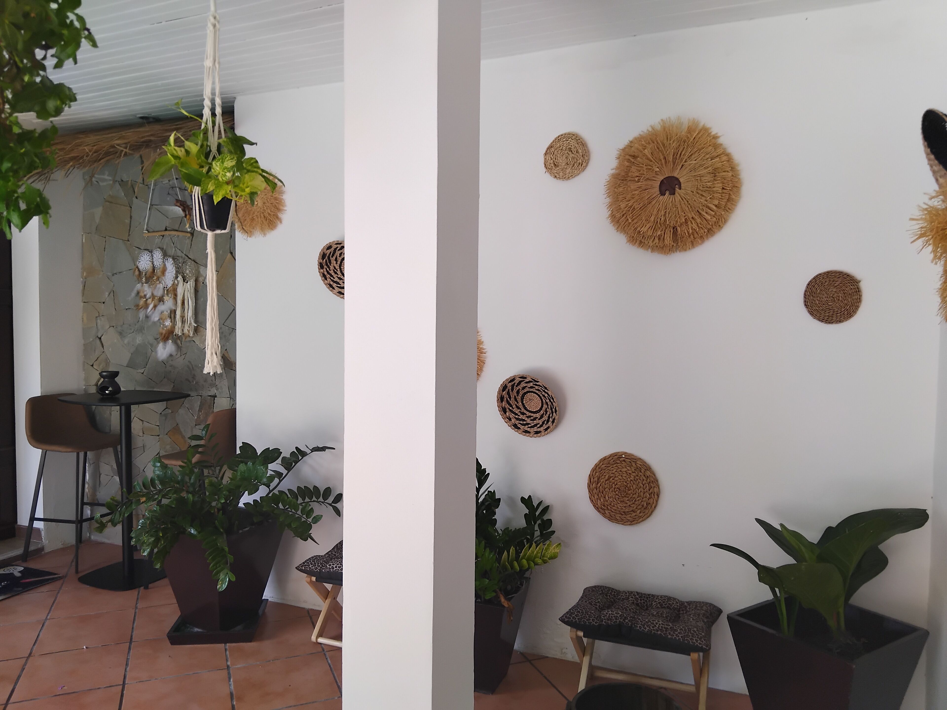 A room with a stone wall, a hanging macrame, a round woven wall decoration, and a potted plant.