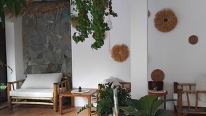 Een kamer met een stenen muur, een houten stoel, een tafel en decoratieve wandversieringen.