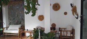 A room with a stone wall, a wooden chair, a table, and decorative wall hangings. - Bohemian-style 4-bedroom villa in Bali with private pool, sauna, and ice bath; beach just a 1-minute walk away (Surat Thani)